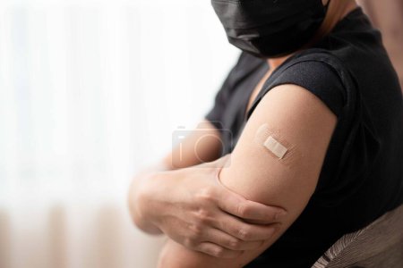 Foto de Hombre con brazo de máscara con vendaje que muestra su brazo después de recibir la vacuna - Imagen libre de derechos