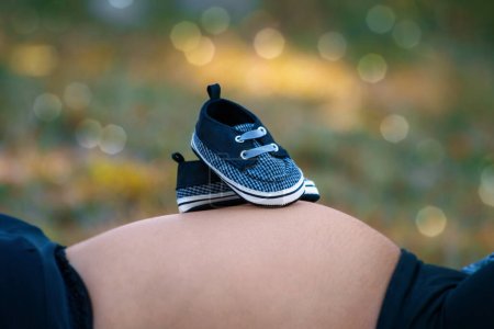Foto de Los zapatos del bebé en el vientre de la mujer embarazada - Imagen libre de derechos