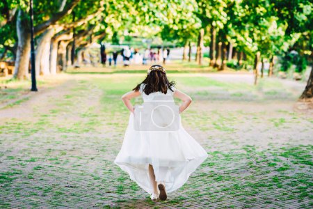Téléchargez les photos : Fille en robe de communion Courir sur le parc - en image libre de droit