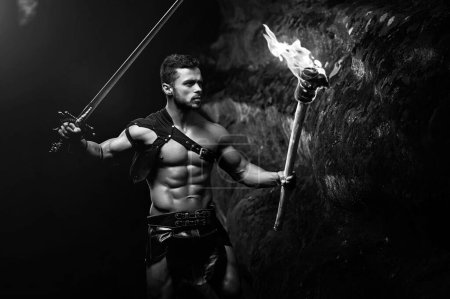 Photo for Fearless young muscular warrior with a torch in the dark - Royalty Free Image
