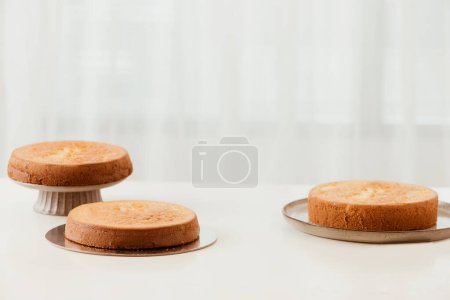Téléchargez les photos : "Trois gâteaux en éponge idéaux faits maison sur une table en bois" - en image libre de droit