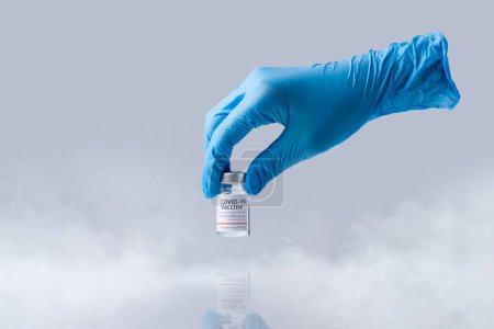 Photo for "Hand holding frozen cold Vaccine vial for Covid-19. Isolated and smoke in Lab theme." - Royalty Free Image