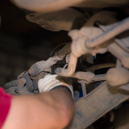 Photo for "The man's hands unscrew the silent block in the chassis of the car." - Royalty Free Image