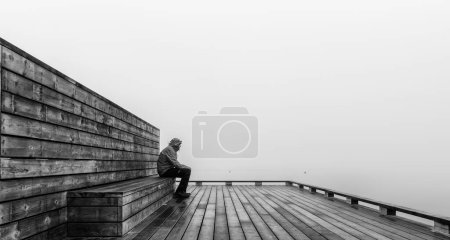 Téléchargez les photos : Homme seul assis sur une jetée en bois - en image libre de droit
