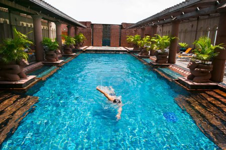 Téléchargez les photos : Homme nageant dans une belle piscine dans l'hôtel. - en image libre de droit