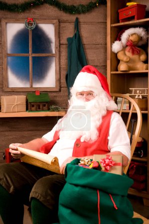 Foto de Santa Claus en mecedora con lista de traviesos - Imagen libre de derechos