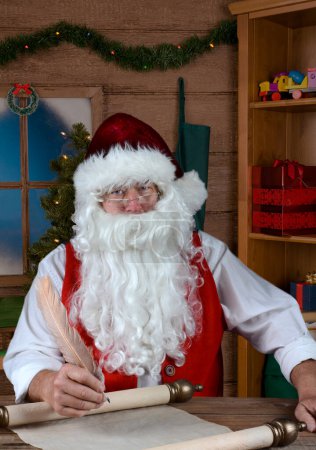 Foto de Santa Claus en su taller escribiendo su Naughty and Nice List. - Imagen libre de derechos
