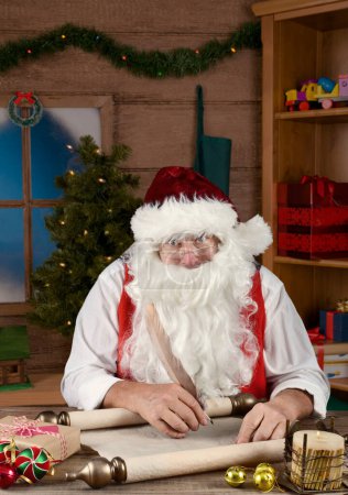 Foto de Santa Claus escribiendo su Lista Traviesa y Niza en su Taller del Polo Norte. - Imagen libre de derechos