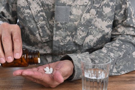 Foto de Concepto militar de abuso de drogas. Primer plano del soldado con tomar pastillas para tratar sus síntomas de TEPT. - Imagen libre de derechos
