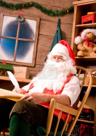 Foto de Santa Claus en taller con pluma de pluma y lista traviesa - Imagen libre de derechos