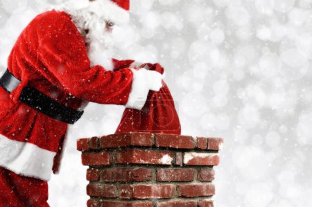Photo for Santa Putting Bag into Chimney - Royalty Free Image