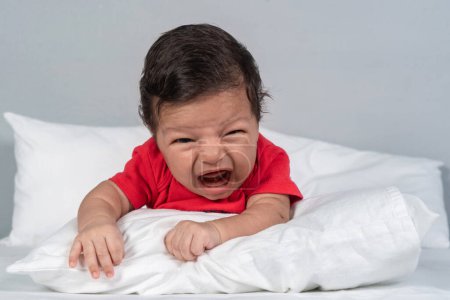 Photo for Crying infant baby on bed - Royalty Free Image