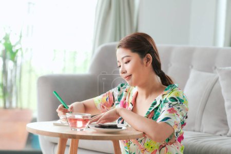 Photo for "Happy wonam writing notes on notebook sitting on  the floor at home" - Royalty Free Image