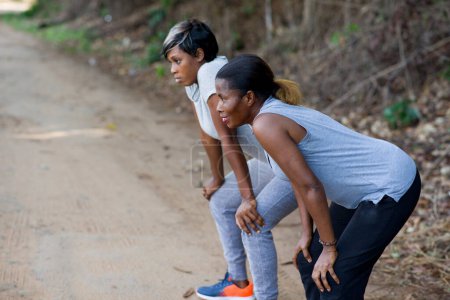 Foto de Dos mujeres corredoras descansando mientras hacen ejercicio en el parque - Imagen libre de derechos