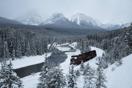 Téléchargez les photos : Train rapide se déplaçant dans les montagnes enneigées en hiver - en image libre de droit