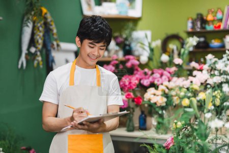 Photo for "One Young Happy Asian Male Florist Working in Shop" - Royalty Free Image