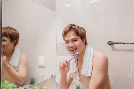 Téléchargez les photos : Jeune asiatique homme avec une brosse à dents dans salle de bain - en image libre de droit