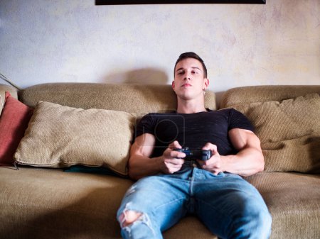 Photo for "Attractive guy playing videogames with joystick in hand" - Royalty Free Image
