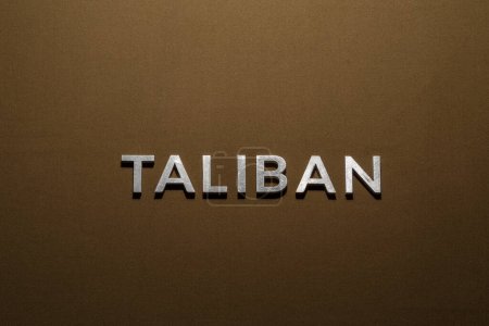 Téléchargez les photos : Mot taliban posé avec des lettres en métal argenté sur tissu de toile kaki tan rugueux - en image libre de droit