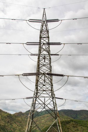 Téléchargez les photos : Image du pylône électrique haute tension et de la ligne électrique de transmission avec le ciel et le fond de montagne - en image libre de droit