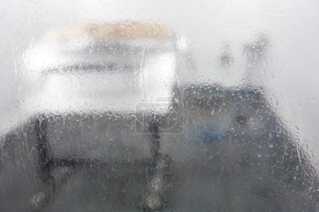 Foto de "Vista a través de vidrio húmedo en las partes de secado del automóvil en cabina de pulverización
" - Imagen libre de derechos