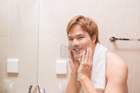 Téléchargez les photos : Homme lavage visage avec nettoyant visage savon de lavage dans l'évier de salle de bain à la maison. - en image libre de droit