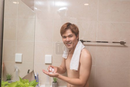 Téléchargez les photos : L'homme verse du lait nettoyant sur sa main - en image libre de droit