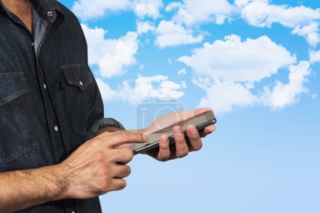 Téléchargez les photos : Homme en utilisant son mobile sur fond de ciel - en image libre de droit