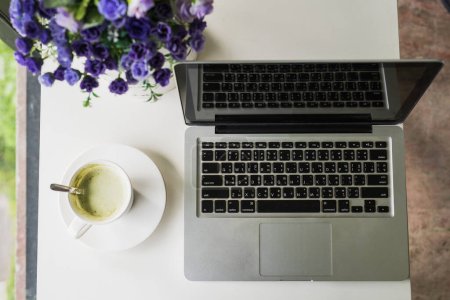 Foto de Cómodo lugar de trabajo en casa con ordenador portátil y café - Imagen libre de derechos