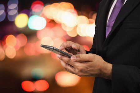 Téléchargez les photos : Homme d'affaires utilisant son téléphone portable nuit lumière route - en image libre de droit