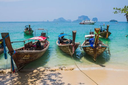 Téléchargez les photos : MAYA BAY, THAÏLANDE - 14 AVRIL 2014 : La géographie karstique dramatique se dresse au-dessus des bateaux thaïlandais traditionnels à queue longue amarrés dans la populaire baie de Maya. - en image libre de droit