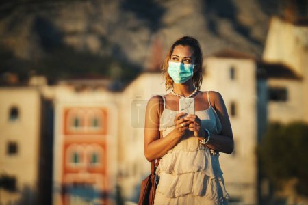 Foto de Retrato de una hermosa mujer joven con máscara de aliento médico en la playa durante la puesta del sol - Imagen libre de derechos