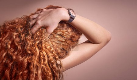 Foto de La mano de la mujer alisa el pelo largo y rizado rojo - Imagen libre de derechos