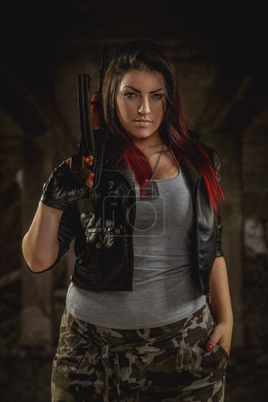 Photo for Portrait of beautiful young woman with gun on dark background - Royalty Free Image