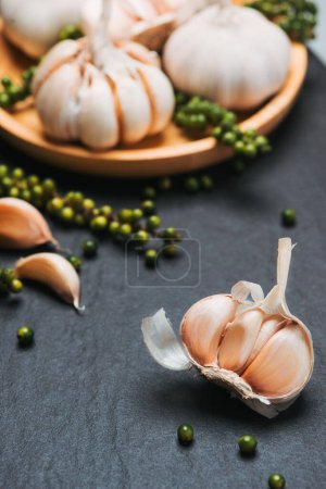Foto de Ajo y granos de pimienta verde en la mesa de piedra negra - Imagen libre de derechos