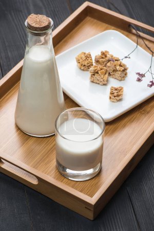 Téléchargez les photos : Produits laitiers. Une bouteille de lait et un verre de lait servent avec des bonbons aux amandes sur une table en bois rustique. - en image libre de droit