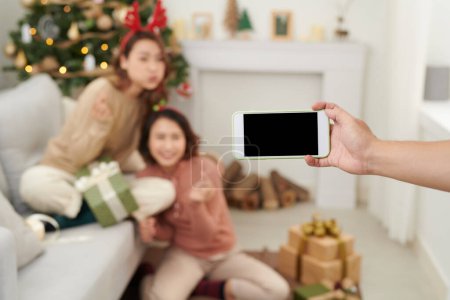 Photo for Attractive girlfriends exchanging gifts at home on christmas eve. - Royalty Free Image