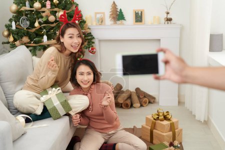 Photo for Cute christmas girls showing presents to the cellphone friends. - Royalty Free Image