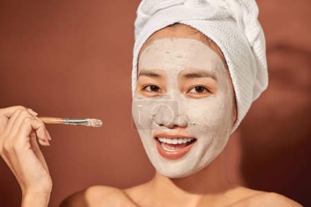 Téléchargez les photos : "Spa Femme appliquant masque d'argile faciale. Soins de beauté. " - en image libre de droit