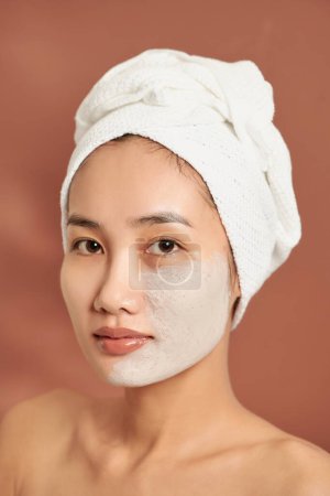Téléchargez les photos : "Spa fille asiatique appliquant masque d'argile faciale. Soins de beauté. Sur fond bleu." - en image libre de droit