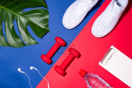Photo for Sport concept. Fitness equipment. Sneakers, water, apple, dumbbell on colorful background. - Royalty Free Image