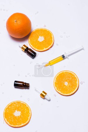 Foto de Una maqueta de marca. Aceite esencial natural, frascos cosméticos con rodajas de naranja
. - Imagen libre de derechos