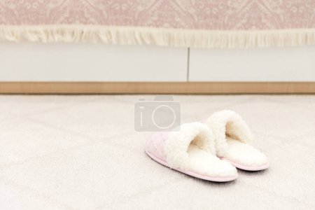 Téléchargez les photos : Chaussons tricotés confortables roses sur tapis de sol - en image libre de droit