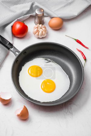 Photo for "Fried eggs in a frying pan with cherry tomatoes and bread for breakfast" - Royalty Free Image