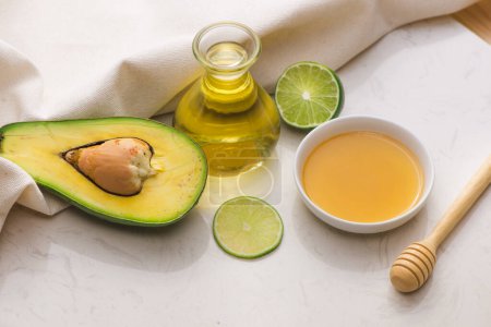 Téléchargez les photos : "Concept d’une alimentation saine. L’huile d’avocat bio frais et citron vert avec du miel sur la table" - en image libre de droit