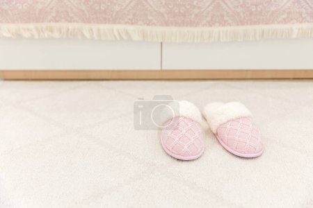 Photo for Pink cozy knitted slippers on floor carpet - Royalty Free Image