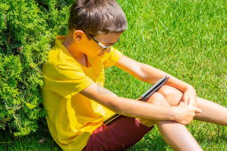 Photo for "Boy studing in a park reading information on a table" - Royalty Free Image