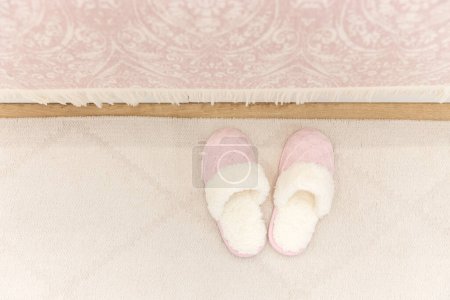 Photo for Pink cozy knitted slippers on floor carpet - Royalty Free Image