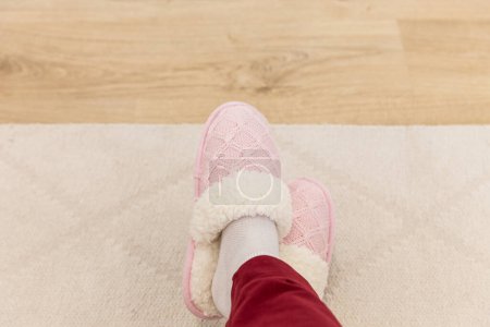 Téléchargez les photos : "Jambes croisées portant des pantoufles tricotées roses" - en image libre de droit