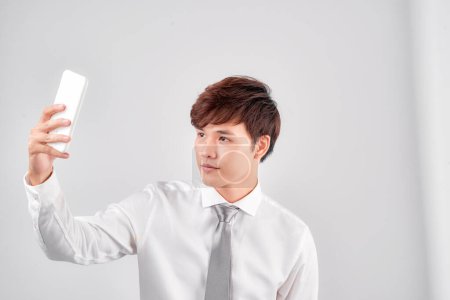 Téléchargez les photos : Asiatique homme prendre selfie sur blanc fond - en image libre de droit